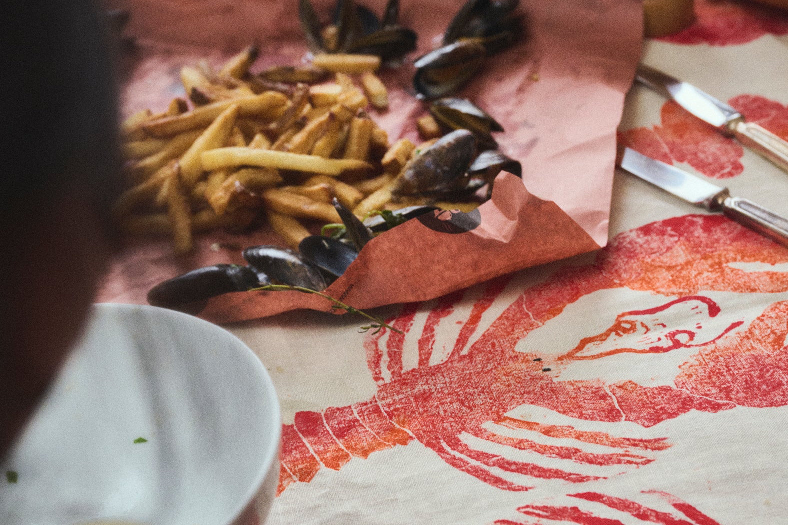 Table setting with food and a decorative tablecloth featuring a lobster design.